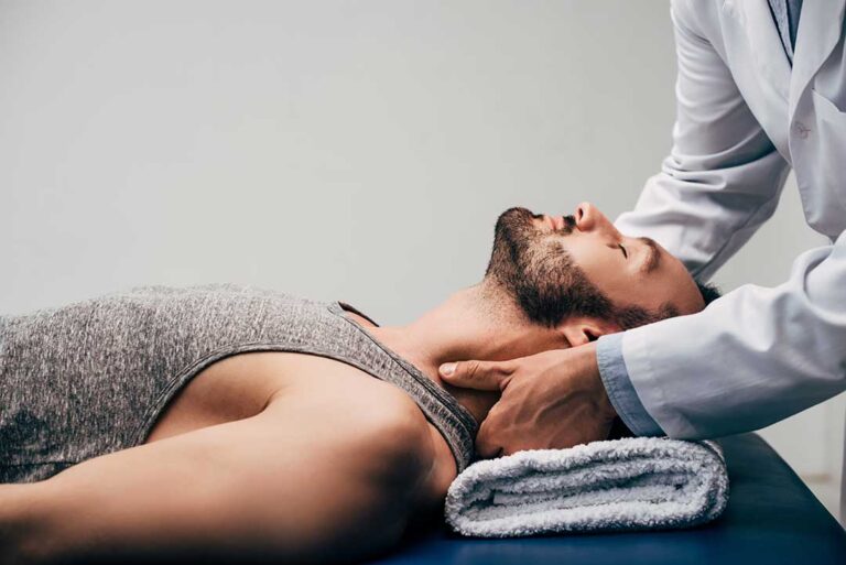 A chiropractor gently adjusting a young athlete’s back in a bright clinic with sports equipment nearby.