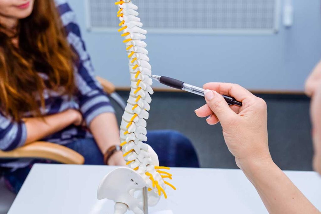 A patient speaking with a chiropractor in a bright office, discussing health history and exam findings.
